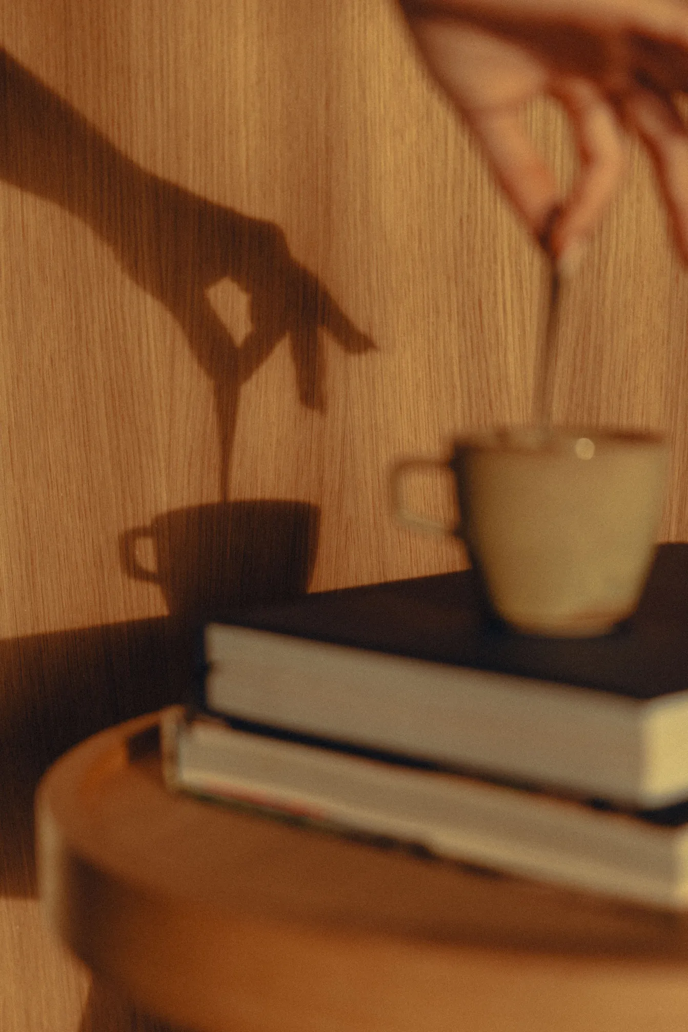 Tasse de café posée sur des livres avec un jeu d'ombres murales, créant une ambiance relaxante dans la chambre Natural Sea.