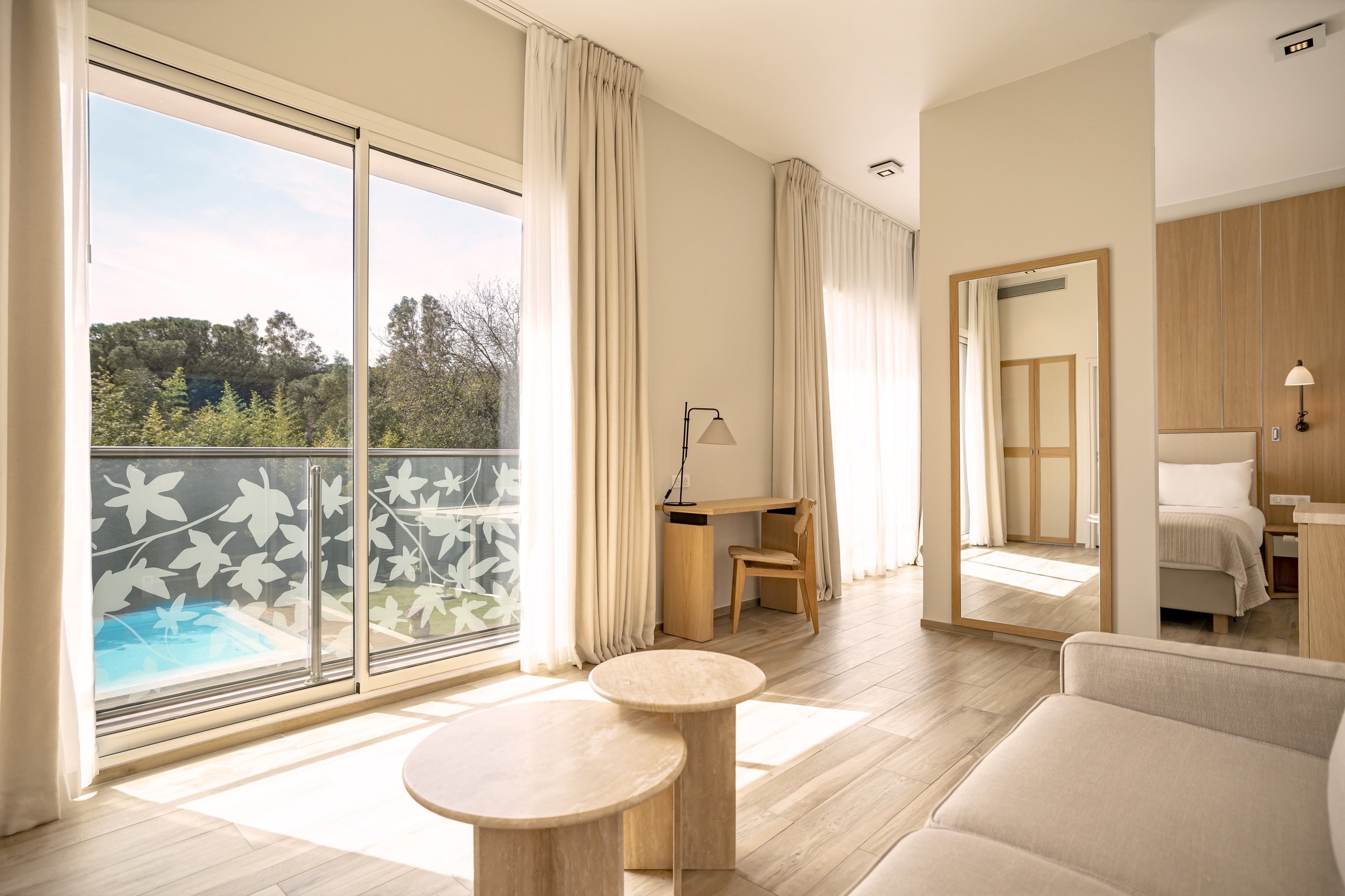 Espace salon spacieux de la suite Prestige Natural avec canapé blanc, tables basses en bois et baie vitrée.