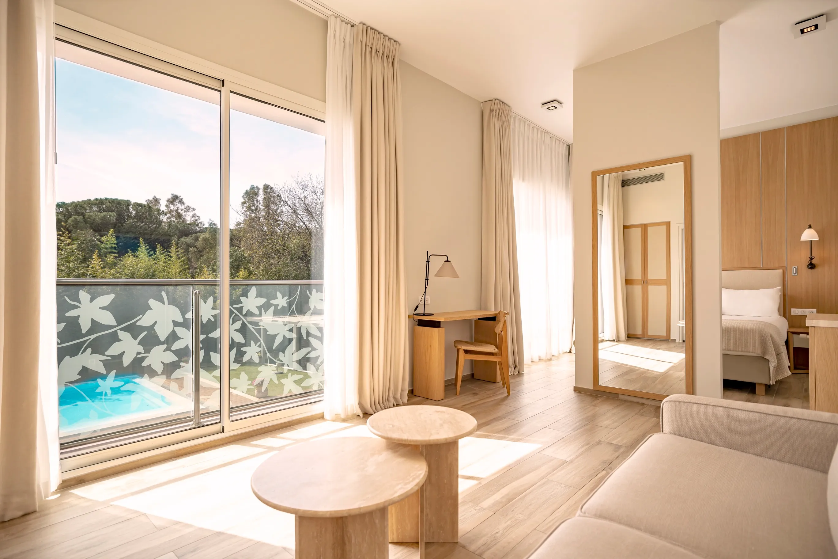 Espace salon spacieux de la suite Prestige Natural avec canapé blanc, tables basses en bois et baie vitrée.