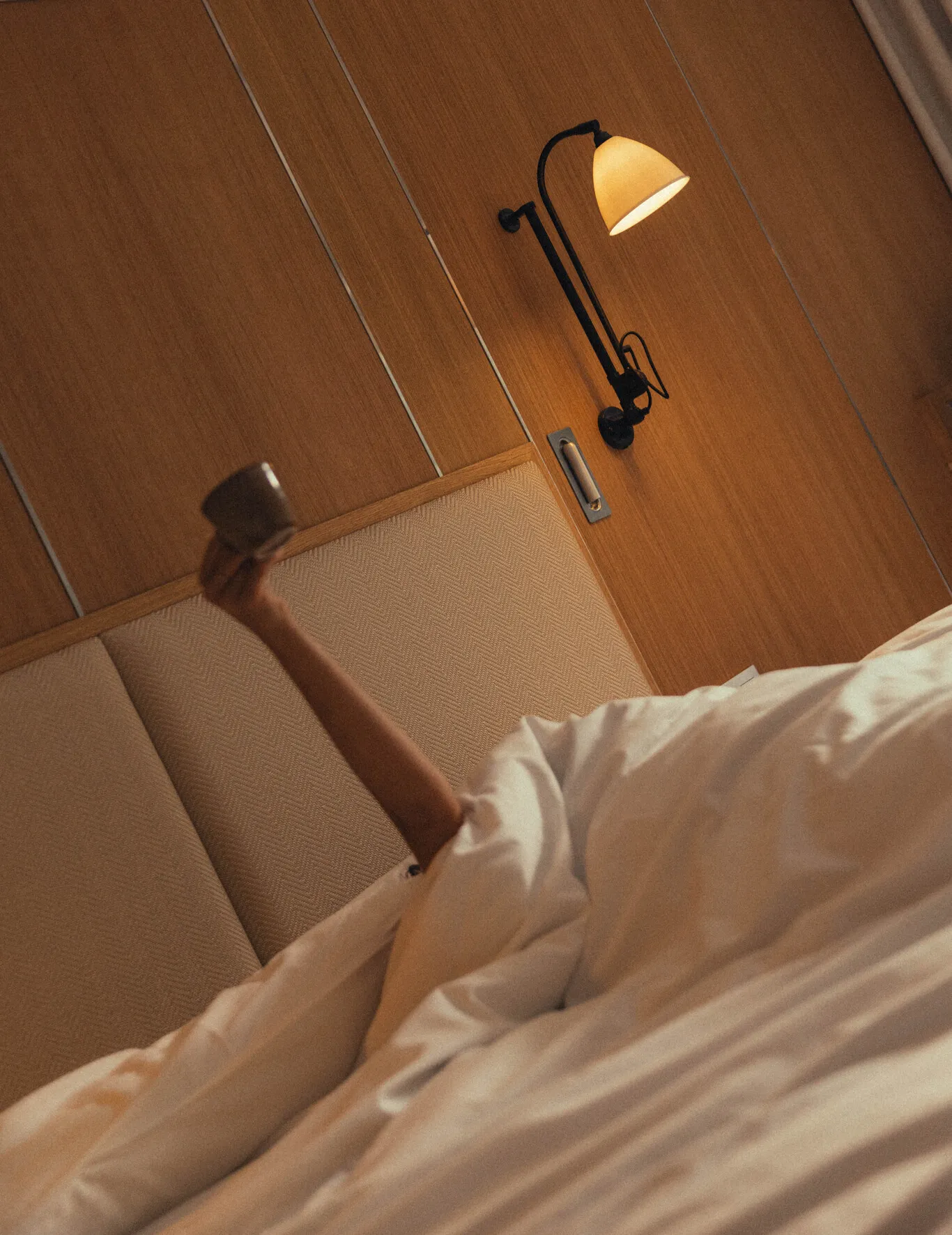 Perspective artistique sur le lit confortable et l'éclairage chaleureux de la chambre Prestige Natural.