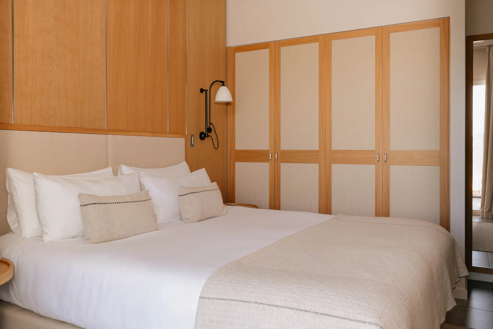 Espace nuit de la chambre Prestige Natural Sea mettant en valeur les grands rangements intégrés en bois de style épuré.