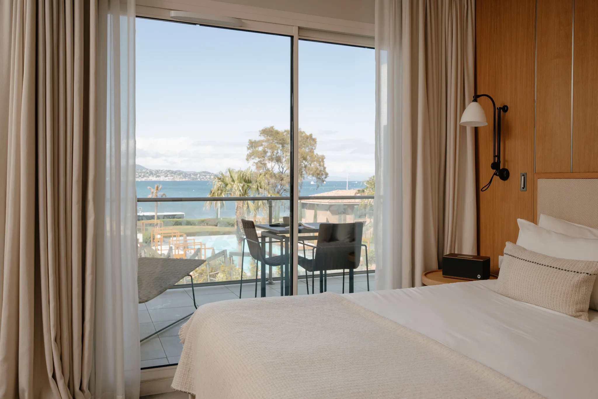 Perspective depuis le lit de la suite Prestige Natural Sea donnant sur un balcon privatif aménagé face à la mer.