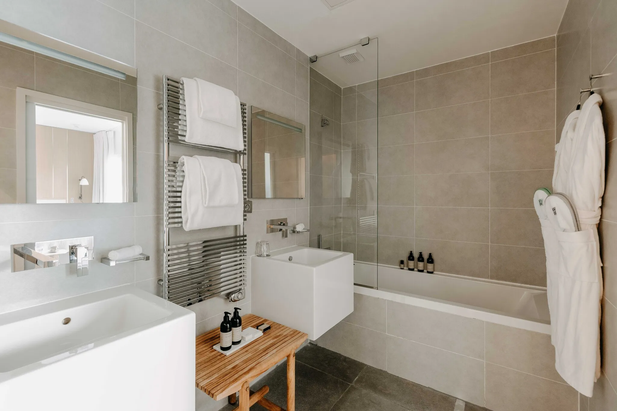 Salle de bain luxueuse avec baignoire, vasques suspendues et finitions grises dans la suite Prestige Natural Sea.