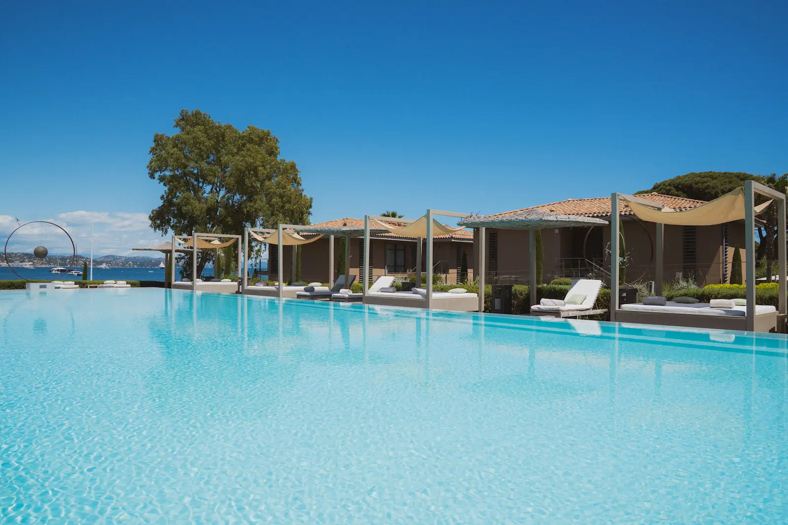 Piscine à débordement du Kube Saint-Tropez face au golfe, daybeds sous voiles d’ombrage
