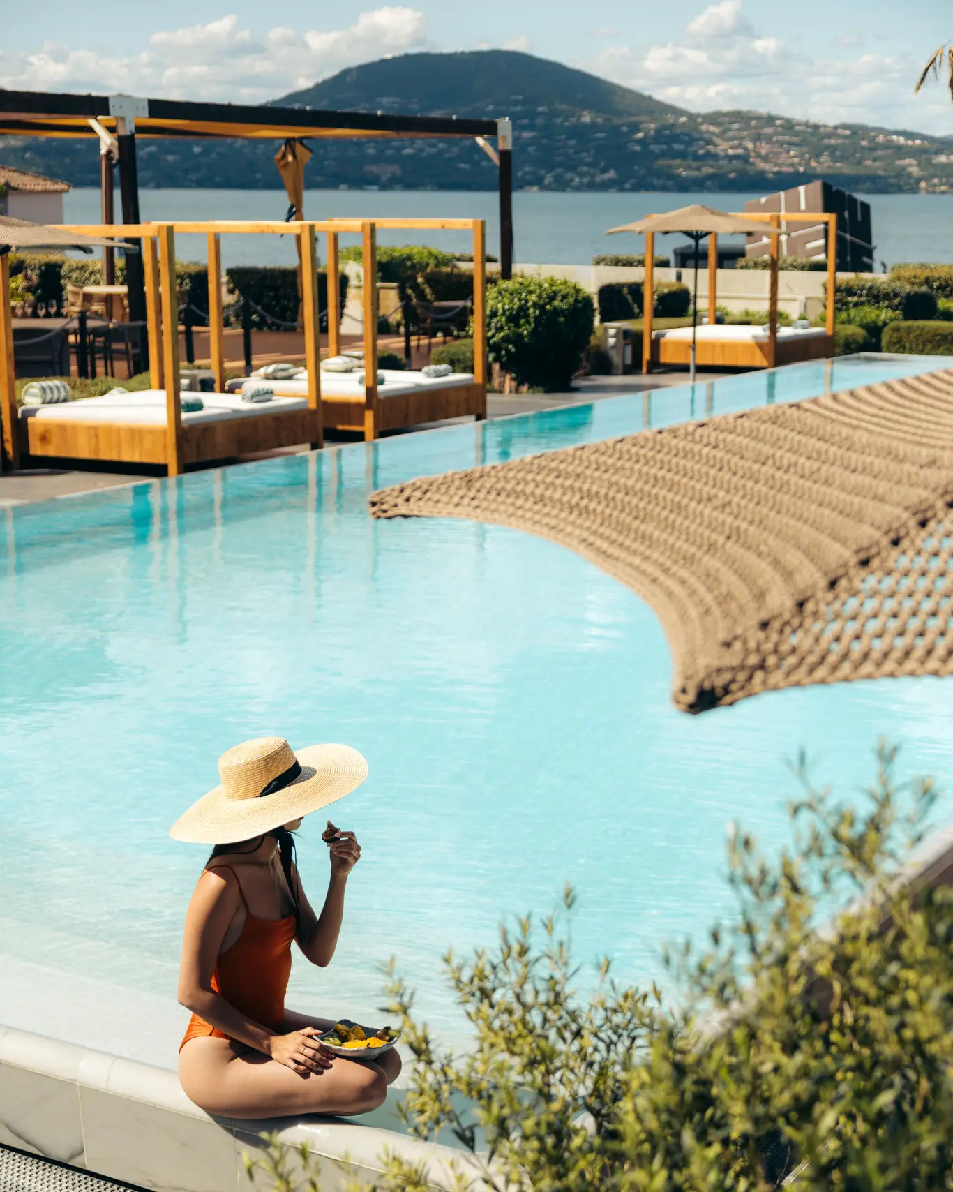 Piscine à débordement du Kube Saint-Tropez face au golfe, daybeds en bois sous pergola