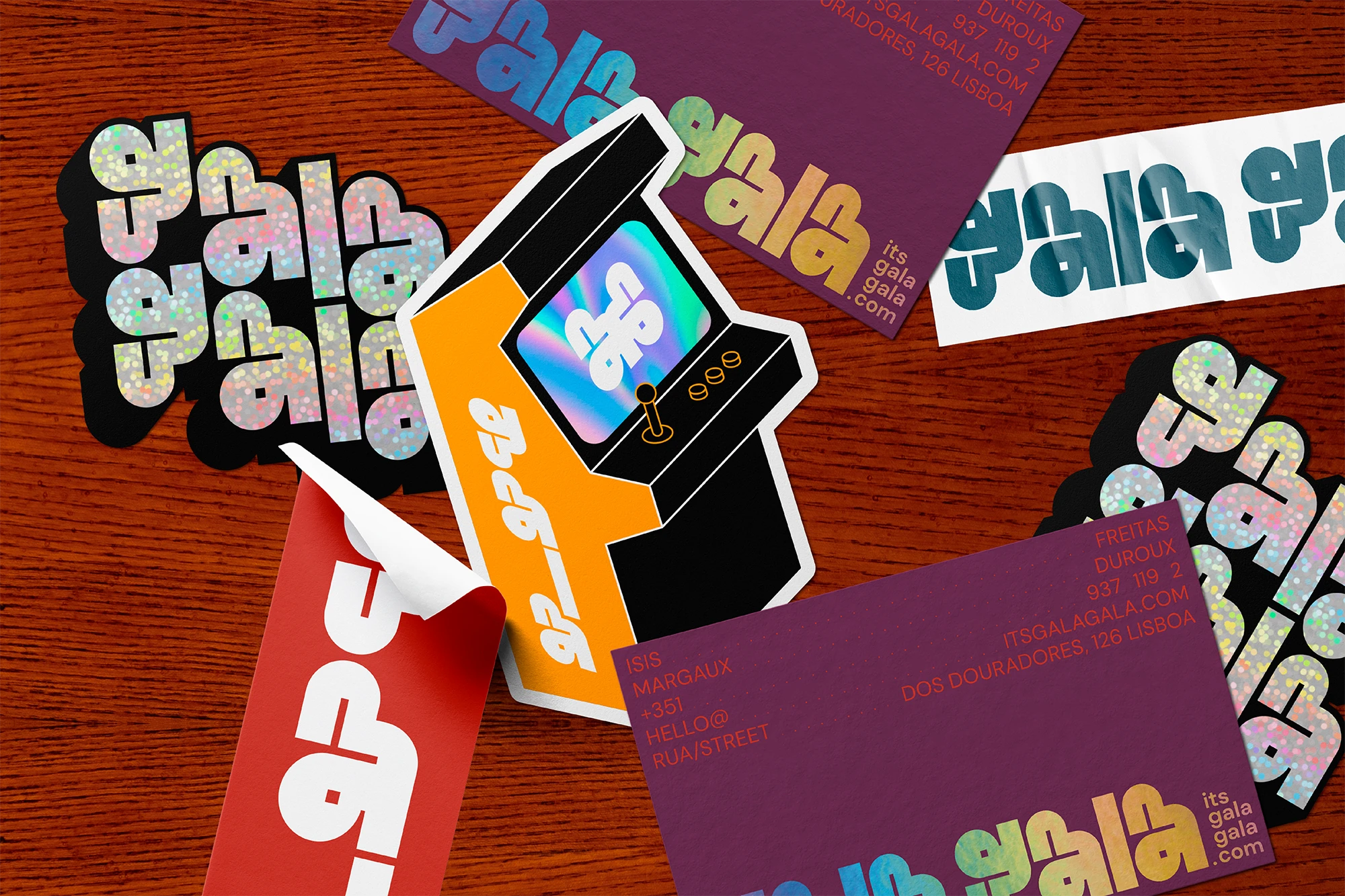 Gala Gala brand stickers and business cards with holographic finish on a wooden surface

