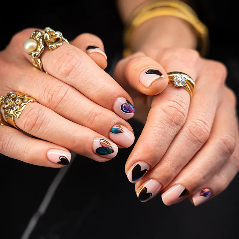 Close-up van nude gelnagels met hartjes en holografisch nagelart bij nagelstudio Lakwerk Amsterdam