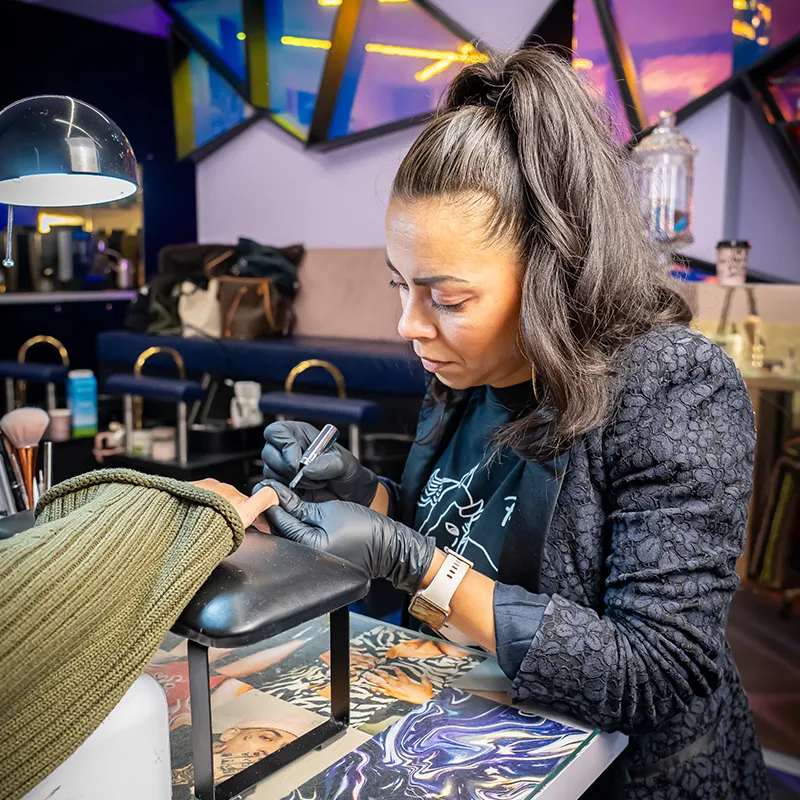 Nagelstyliste van Lakwerk voert geconcentreerd een nagelbehandeling uit bij een klant in Amsterdam