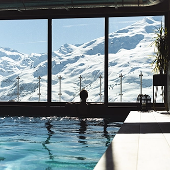 Femme dans la piscine face aux montagnes