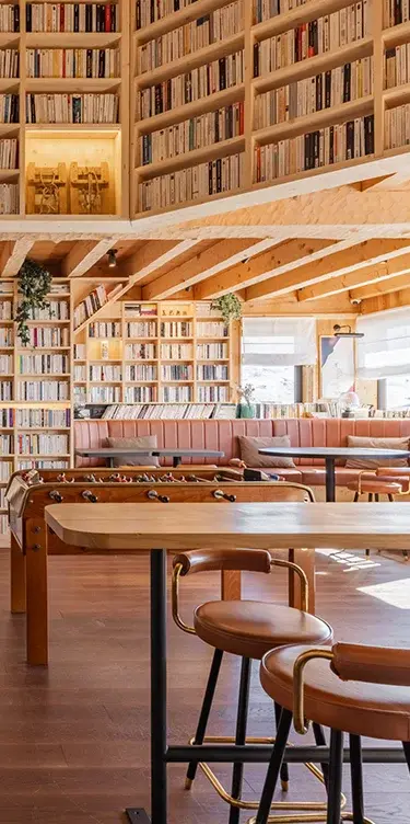Hotel lobby with a babyfoot table, seat and tables and its library filled with books