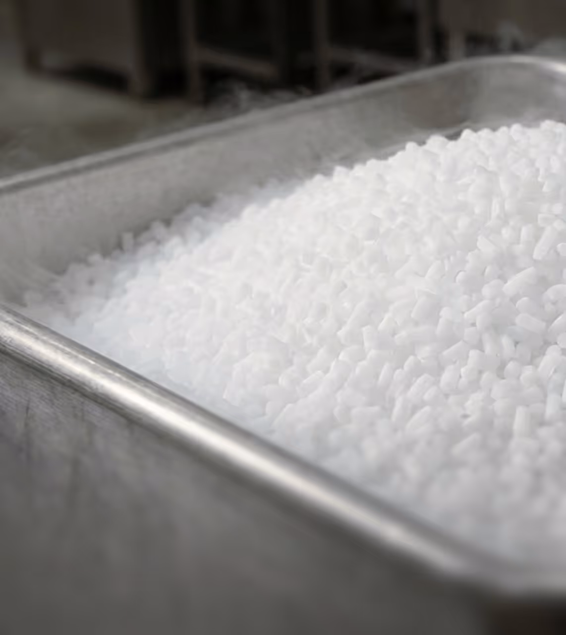 Metal tray filled with small white pellets emitting light vapor.