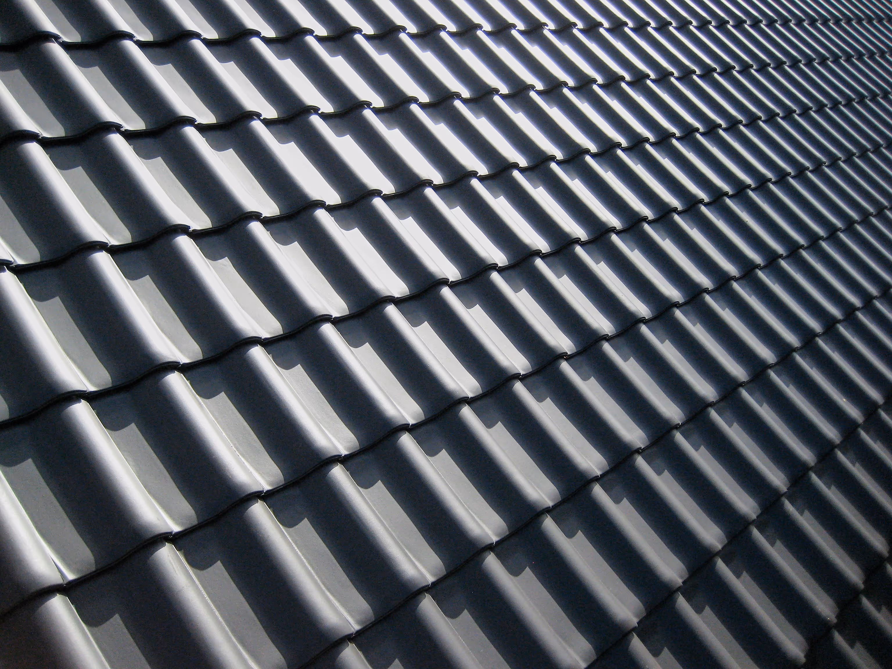 Close-up of gray concrete tile roofing installed in an overlapping wave pattern
