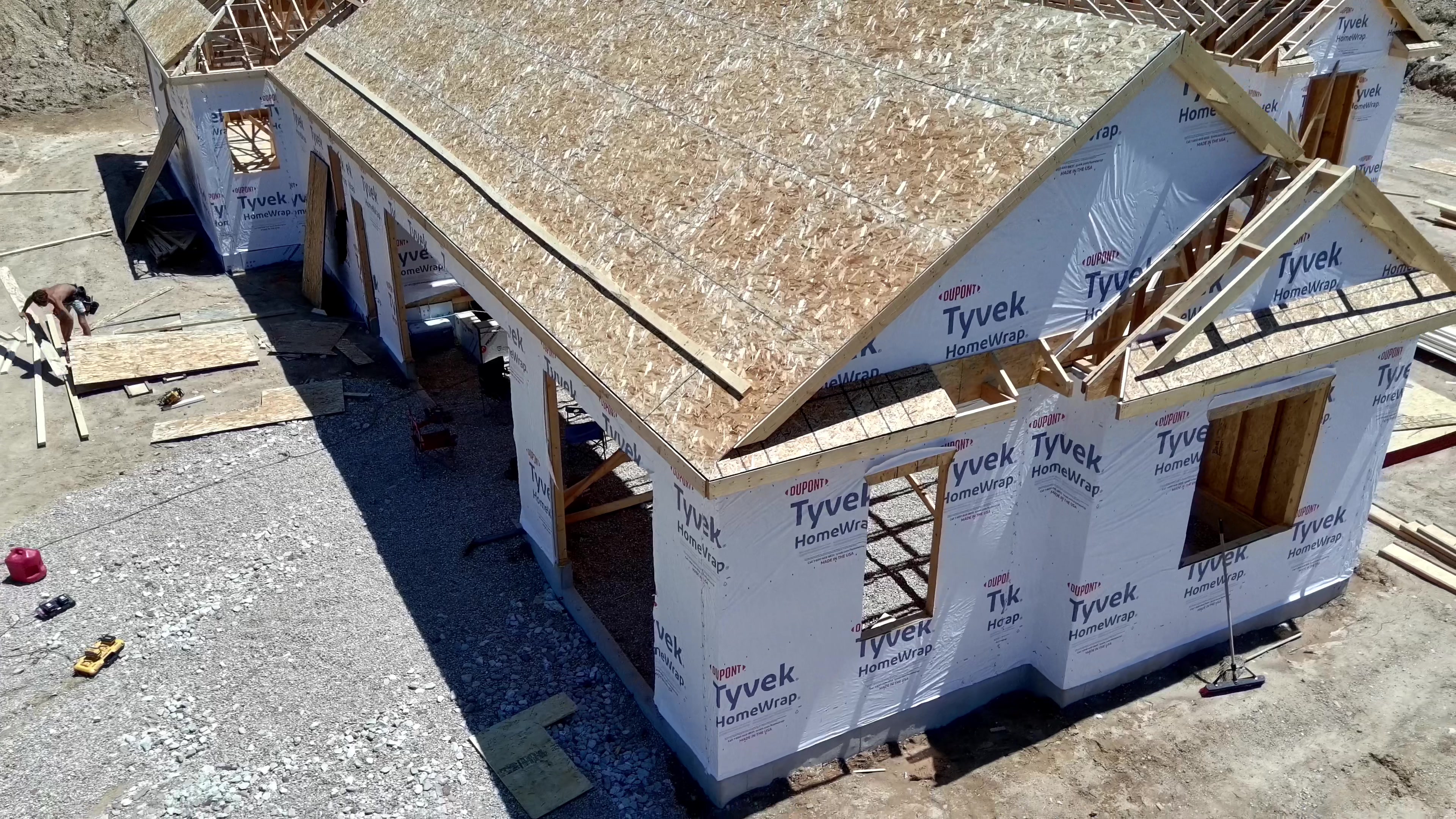 Aerial view of new home roof framing and exterior walls wrapped in Tyvek weather barrier during construction