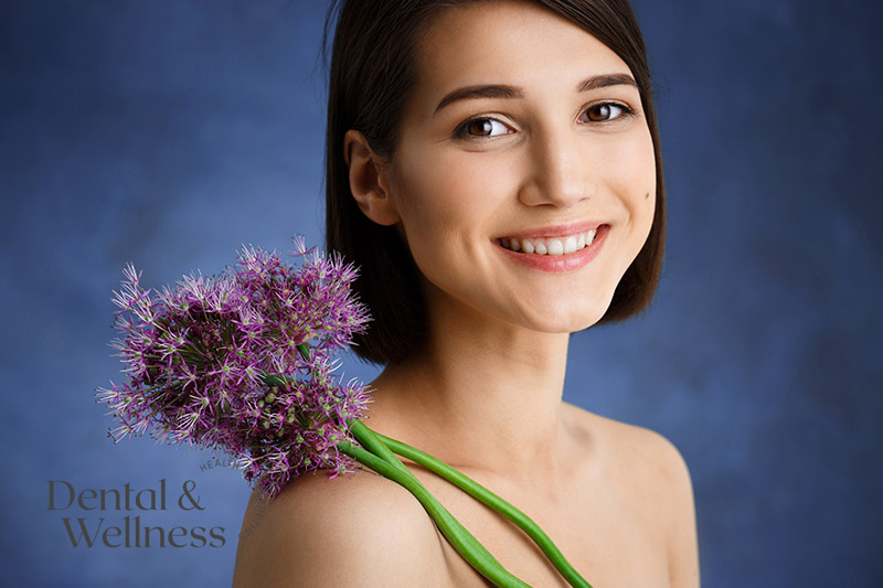 Smiling young woman holding purple allium flowers — subtle anti-wrinkle treatment