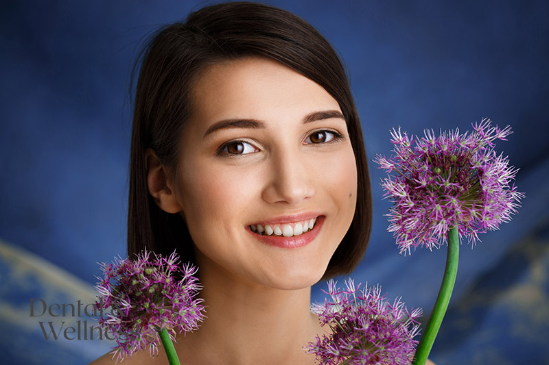 Smiling young woman framed by purple allium flowers