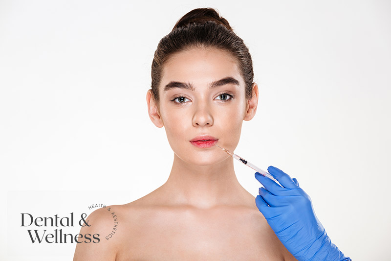 Gloved hand holding a syringe beside a young woman's lips
