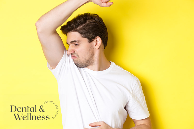 Man grimacing at a sweat patch under his raised arm — excessive sweating treatment
