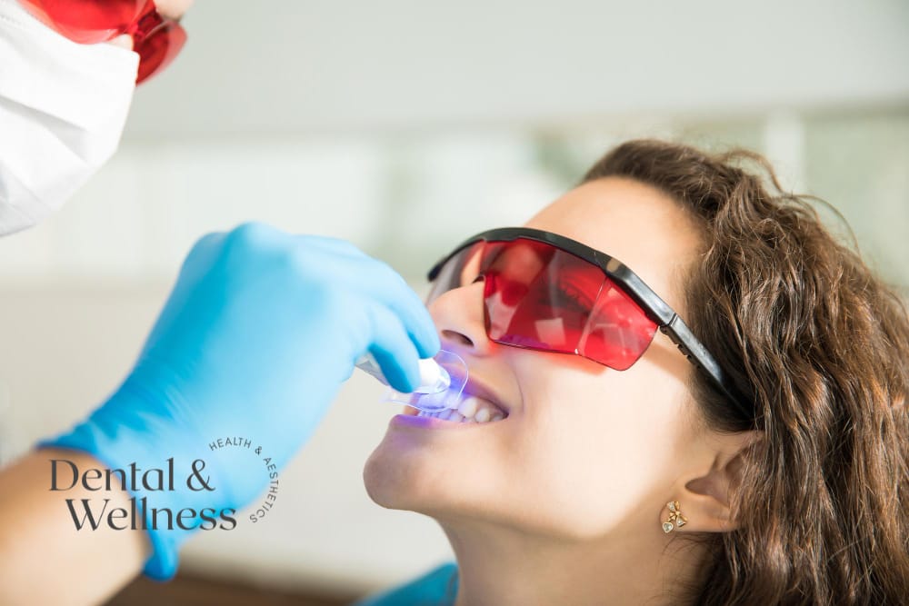 Patient in protective glasses having a curing light used on her front teeth