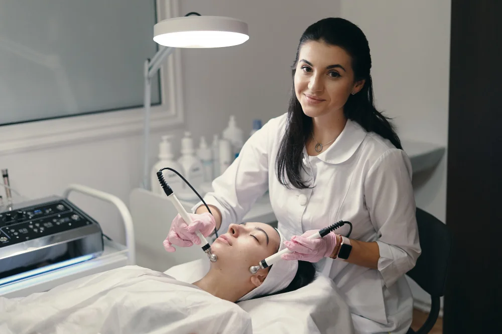 Therapist carrying out a facial treatment with two handheld devices