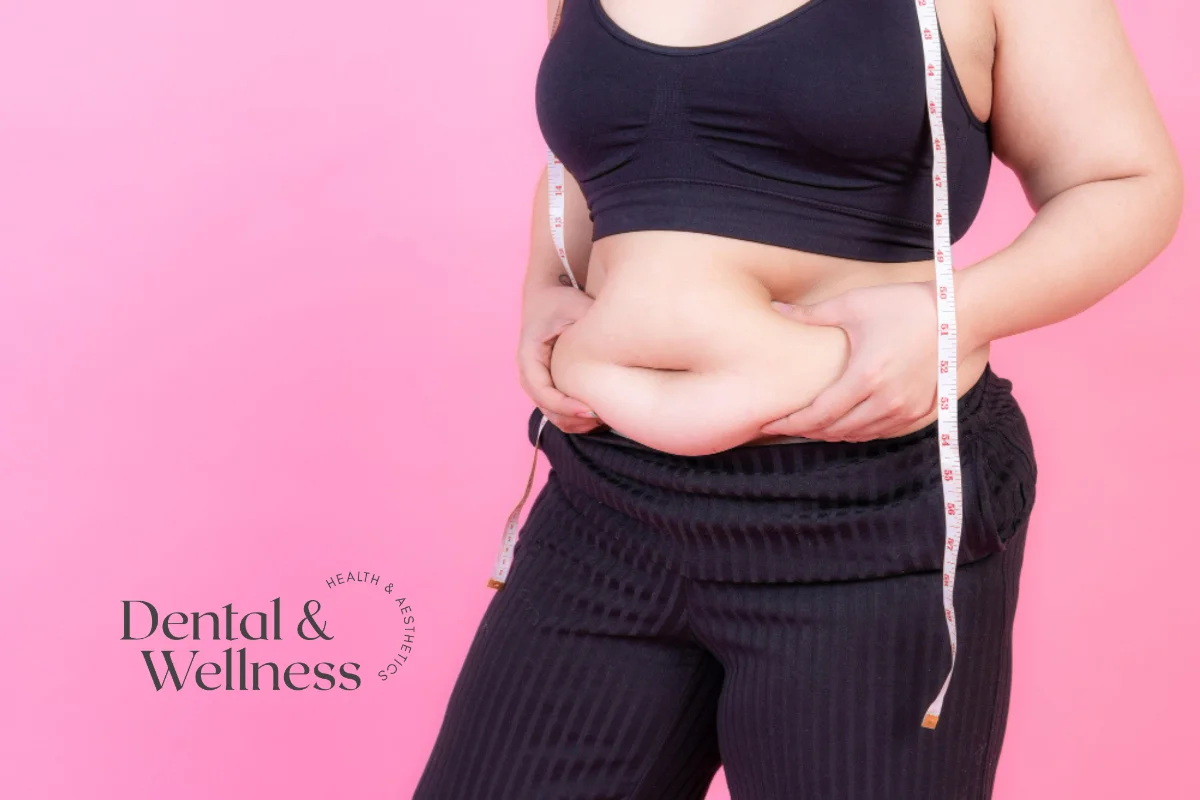 Body sculpting safety: woman holding the skin around her waist with a tape measure over her shoulder