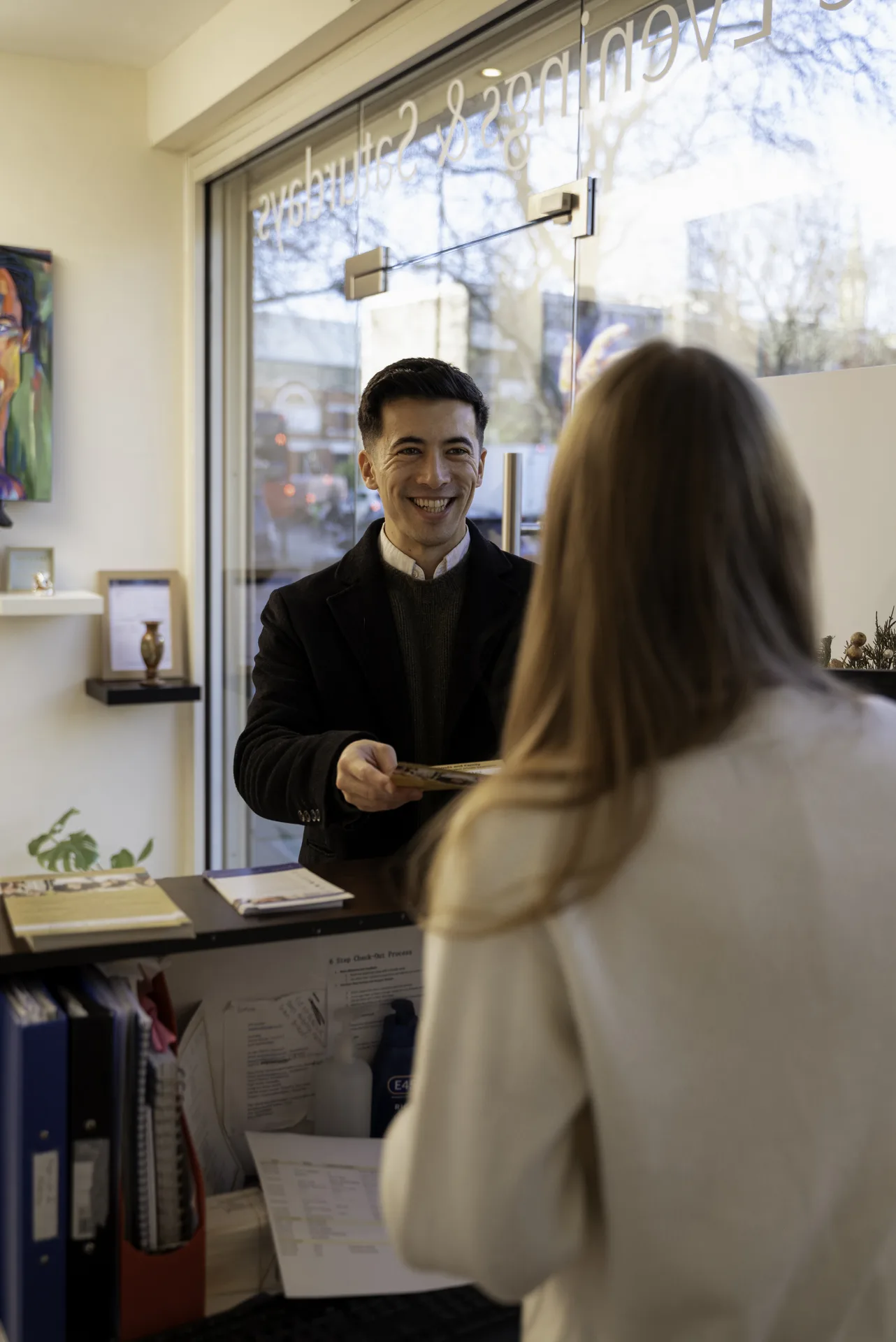 Receptionist welcoming a patient at the front desk — private dentist