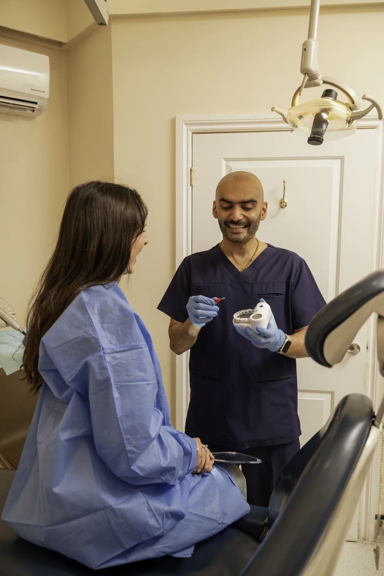 Dentist speaking with a patient in a treatment gown seated in the chair — Davies hard stabilisation splint