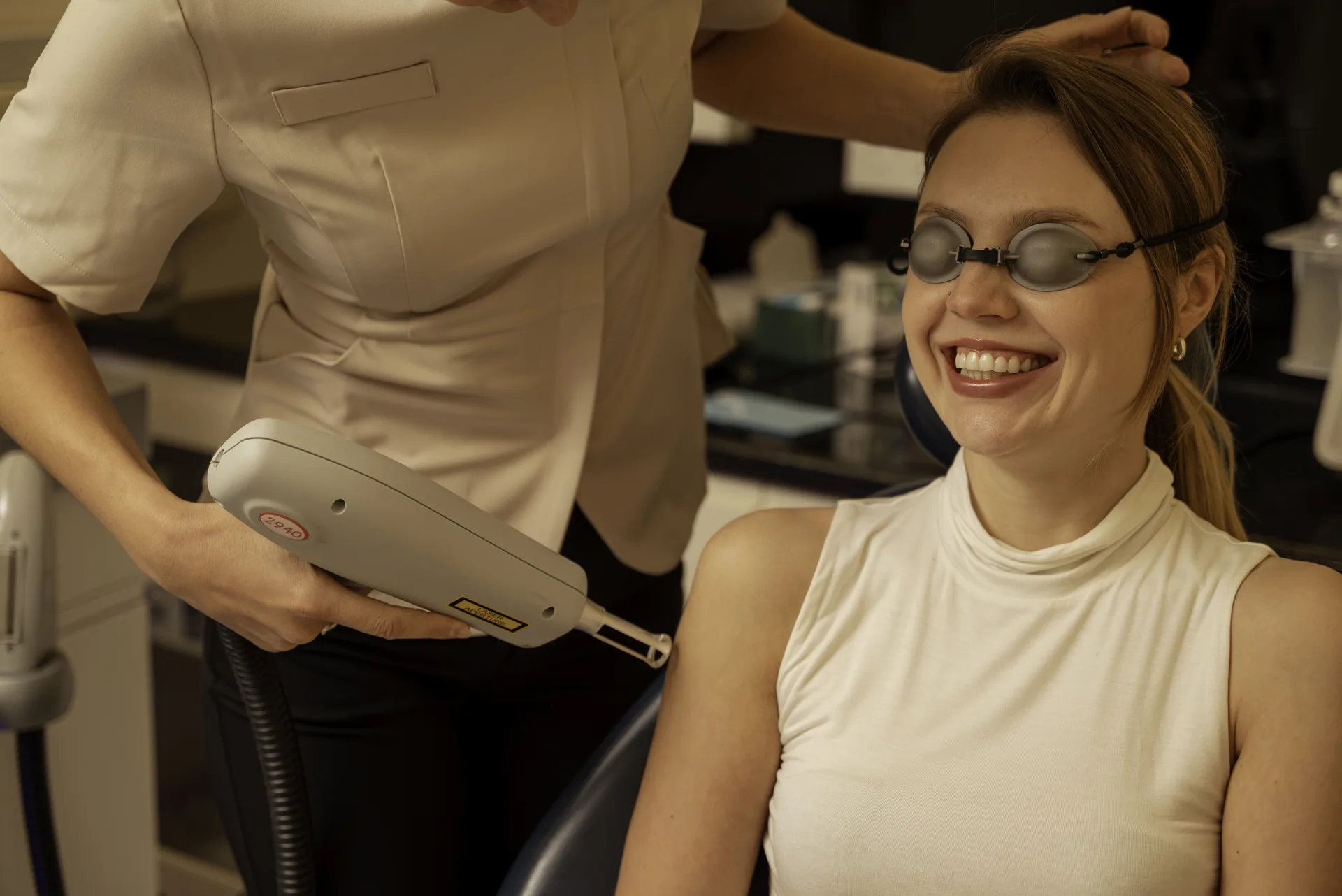 Smiling patient in protective glasses as the therapist prepares a laser handpiece — PicoSure alternative