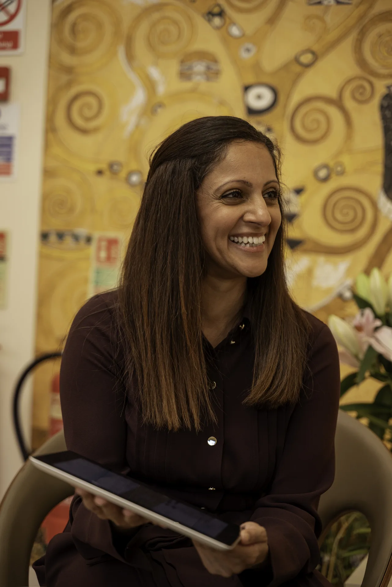 Wellness practitioner smiling in the clinic lounge, holding a tablet — meditation classes