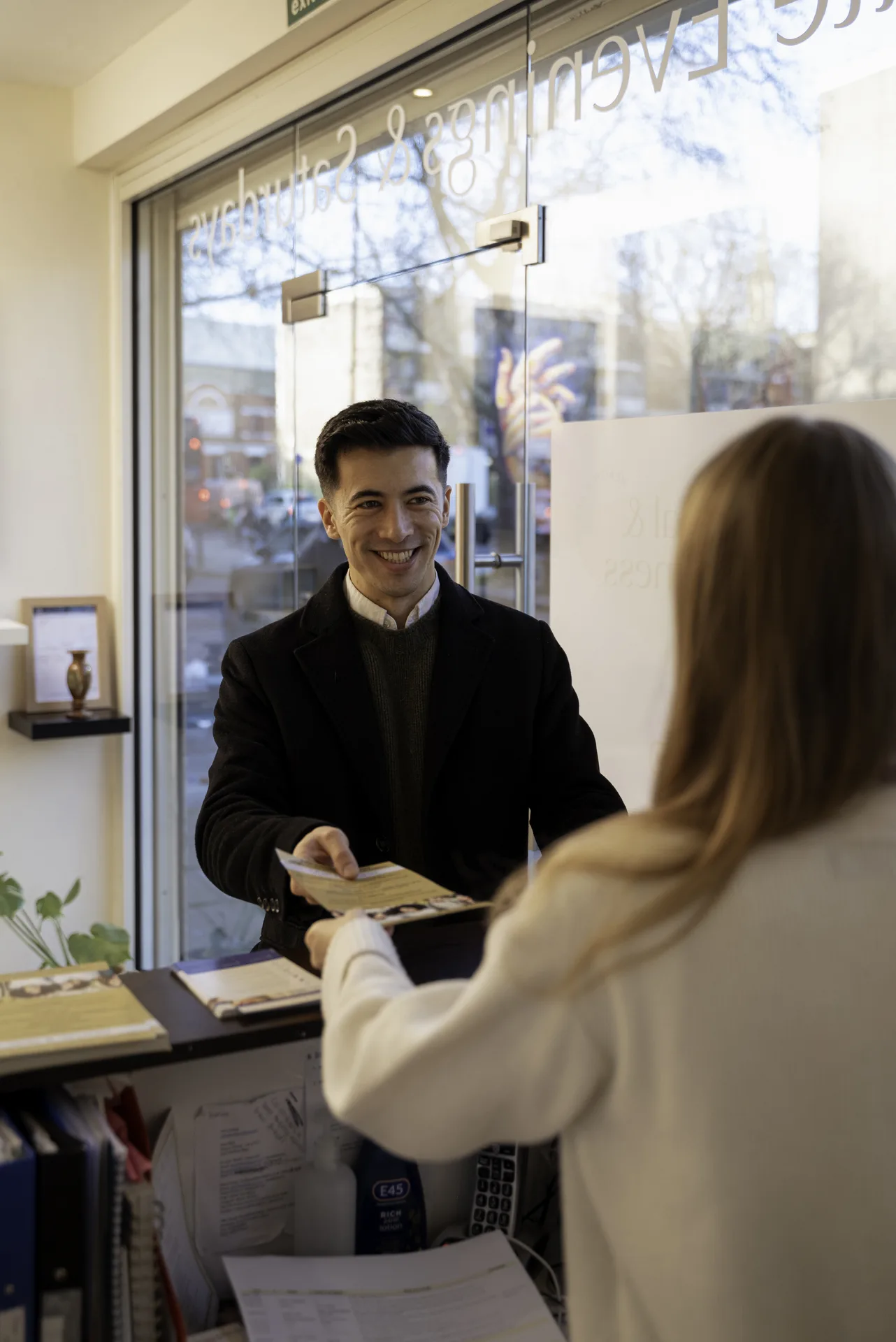 Receptionist welcoming a patient at the front desk — dentist for Hackney