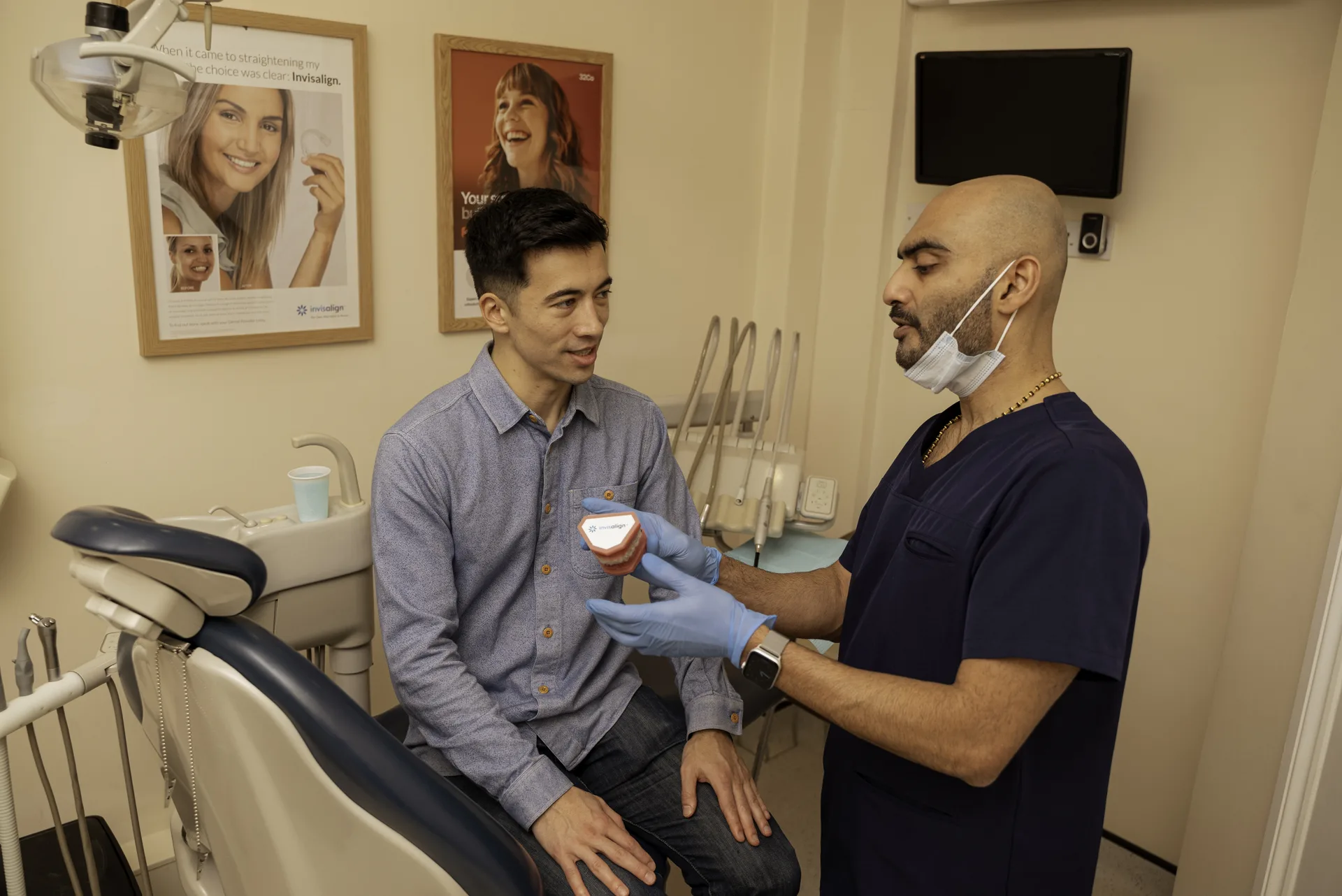 Dentist explaining a dental model to a patient seated in the chair — dental implant aftercare