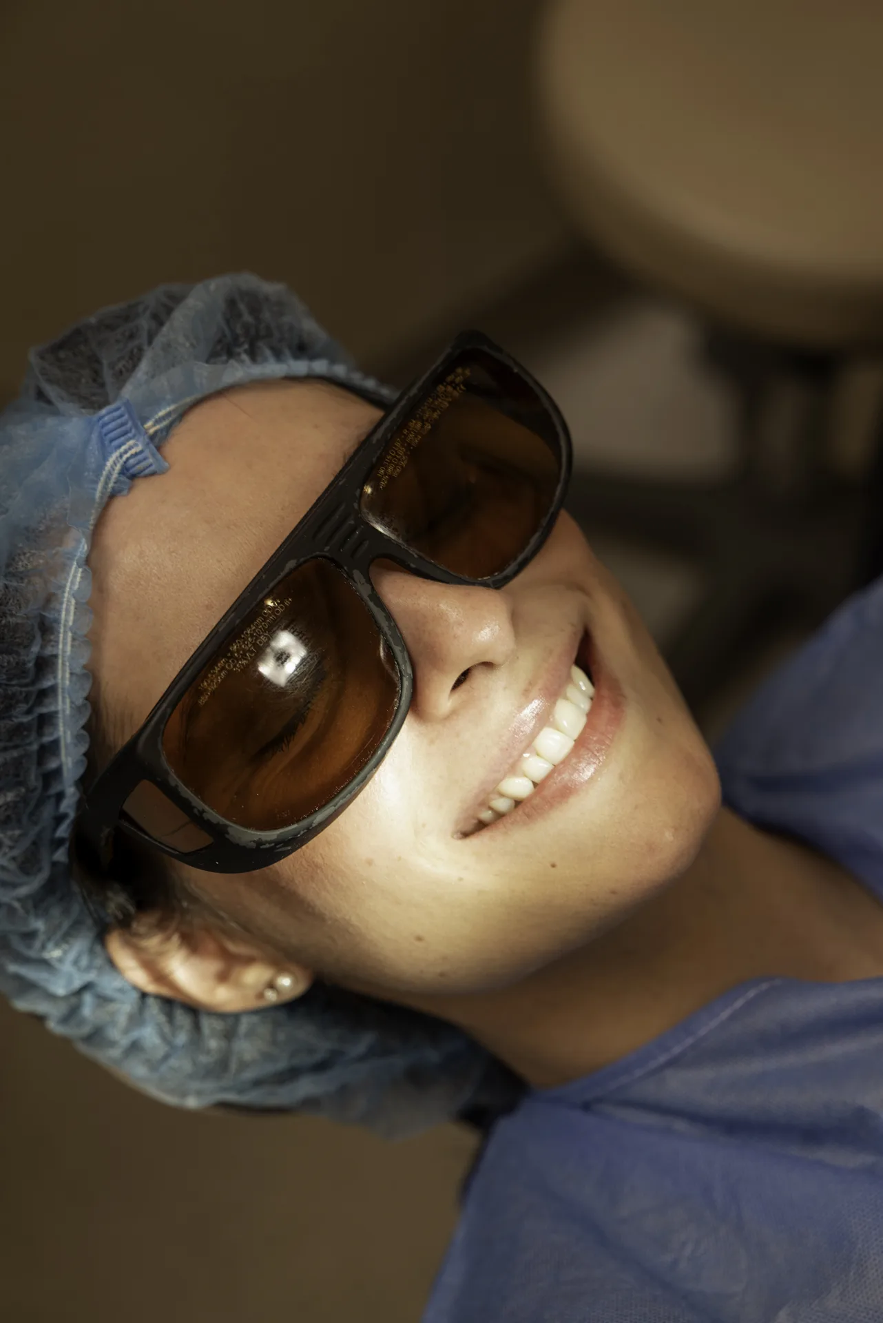 Smiling patient in protective glasses under the whitening light — Zoom whitening vs home whitening