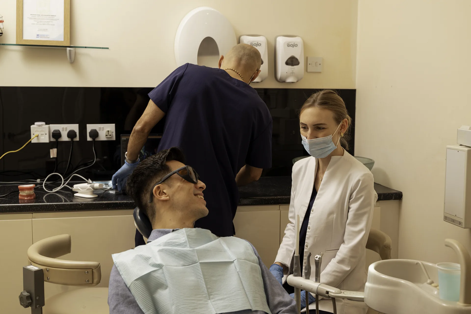 Dentist and nurse talking with a patient in protective glasses in the dental chair — wisdom tooth removal