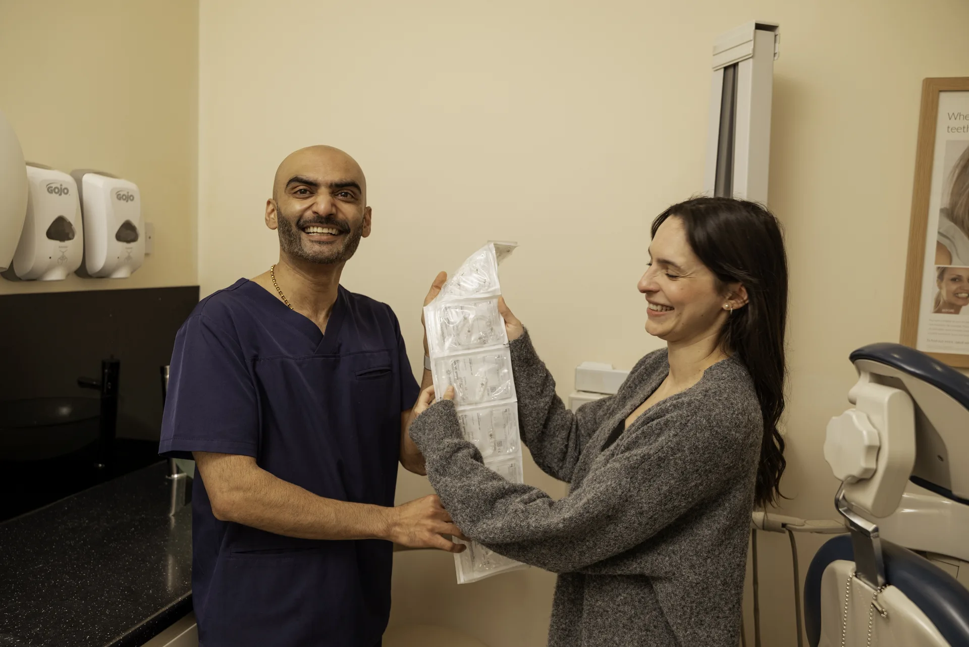 Dentist handing a smiling patient her clear retainer in the surgery