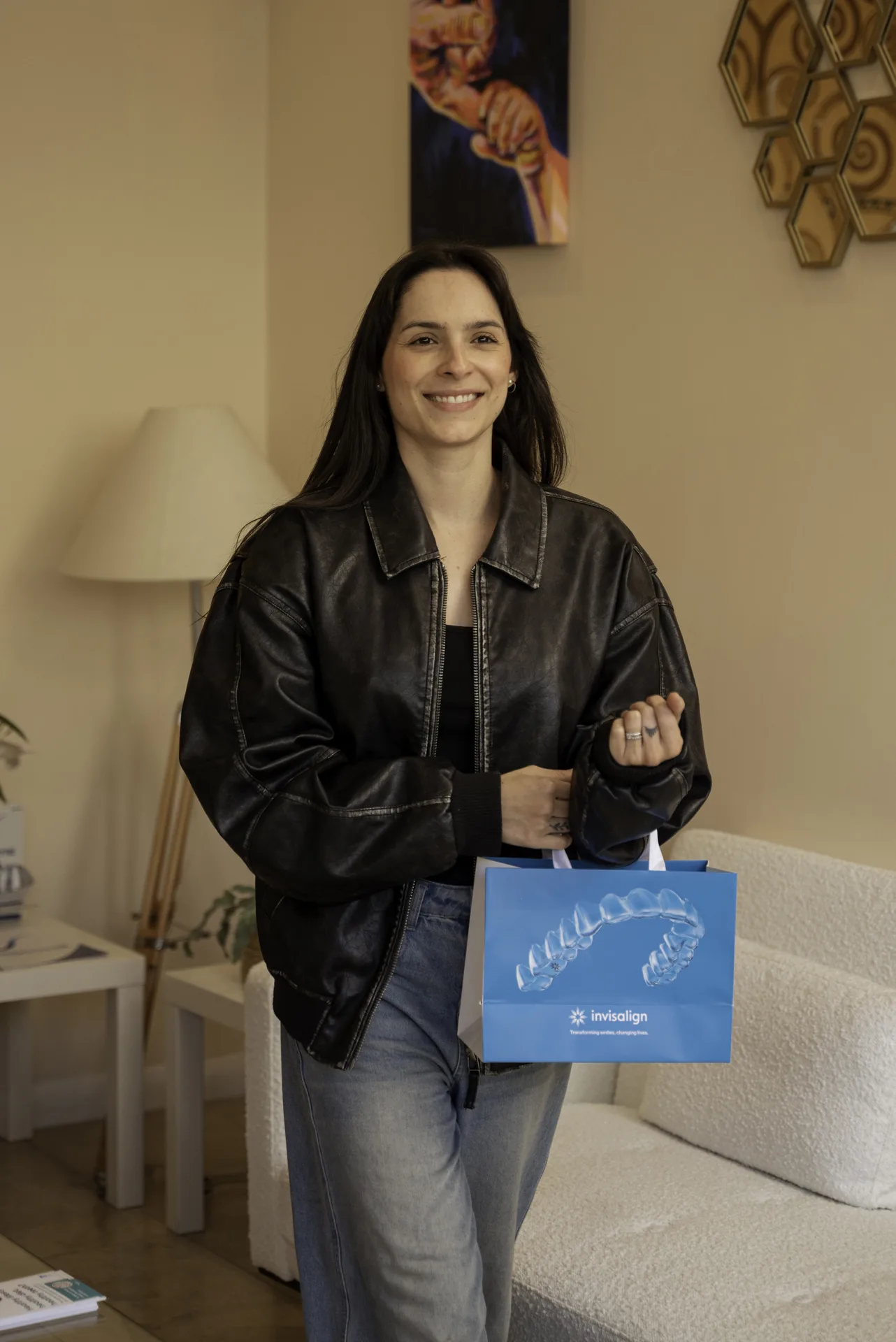 Patient leaving the clinic smiling, carrying an Invisalign bag