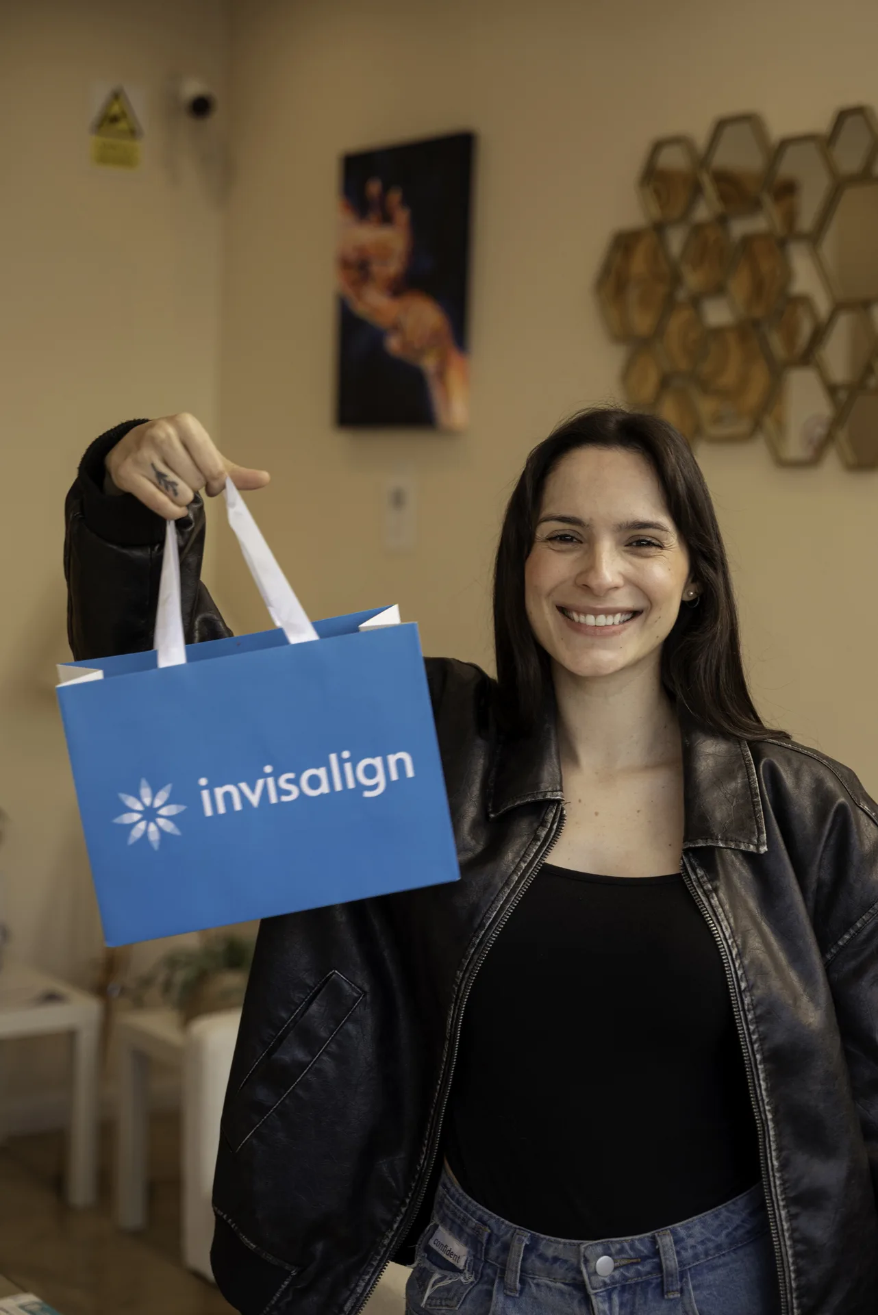 Invisalign attachments: smiling patient holding up an Invisalign bag in the clinic reception