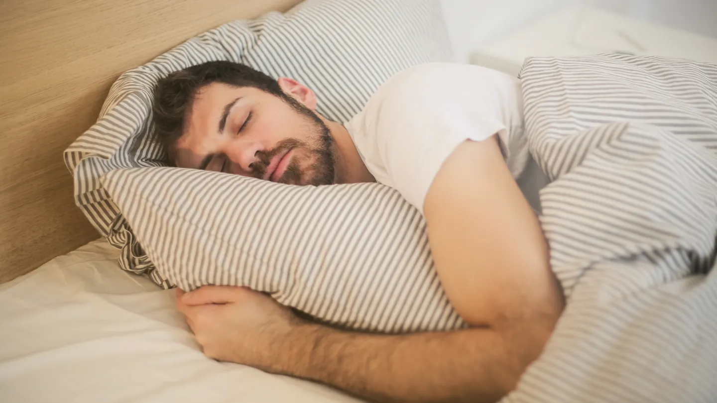 Snoring treatment: man asleep in bed with his mouth open