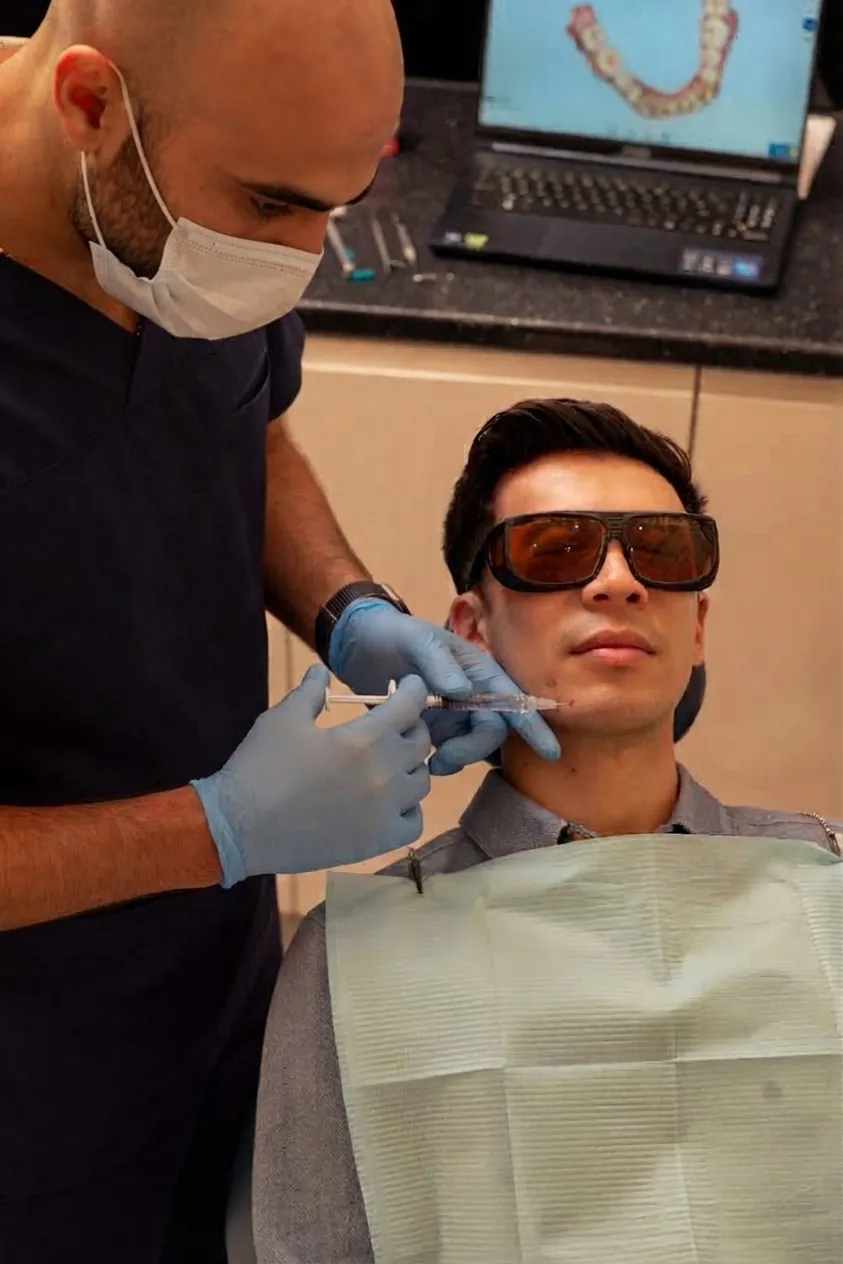 Chin filler in Islington, London: clinician examining the lower face of a patient in protective glasses