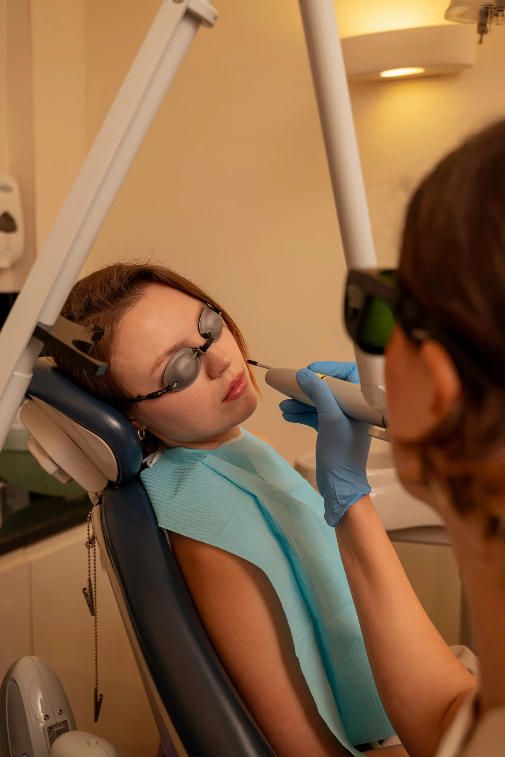 Acne treatment in Islington, London: therapist in protective glasses treating a reclining patient's face