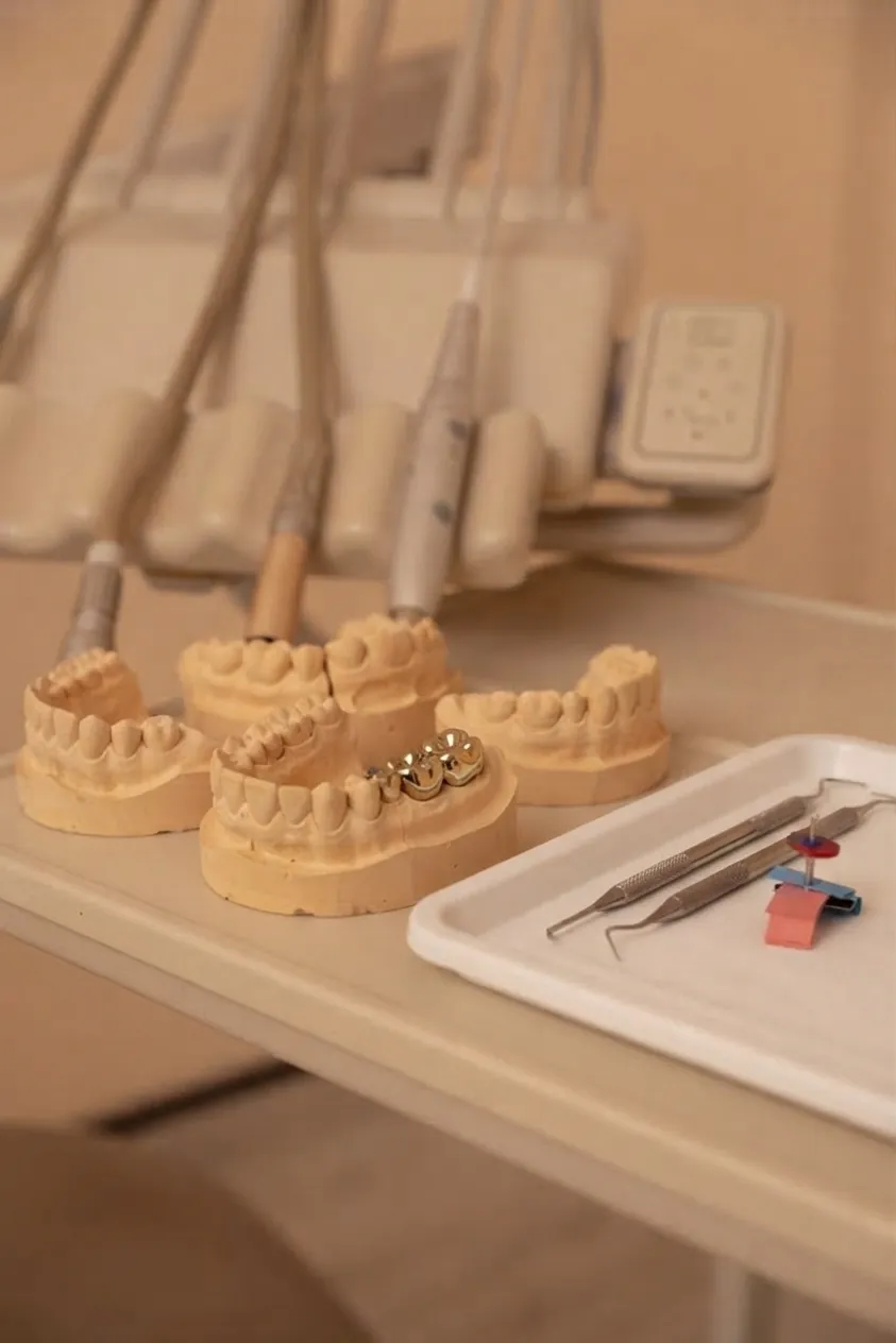 Implant vs bridge: plaster dental models and instruments on a tray in the surgery