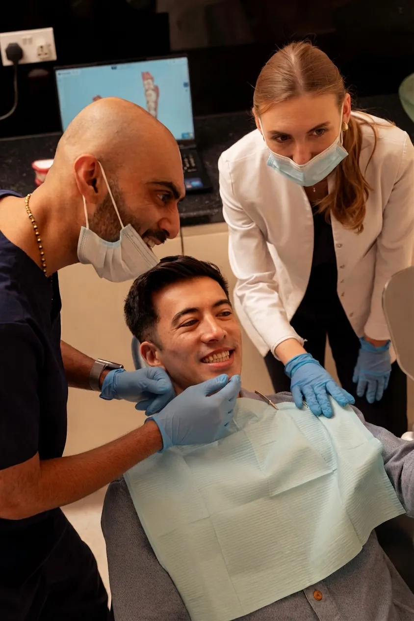 Dentist and nurse examining a smiling patient's teeth in the chair — mewing