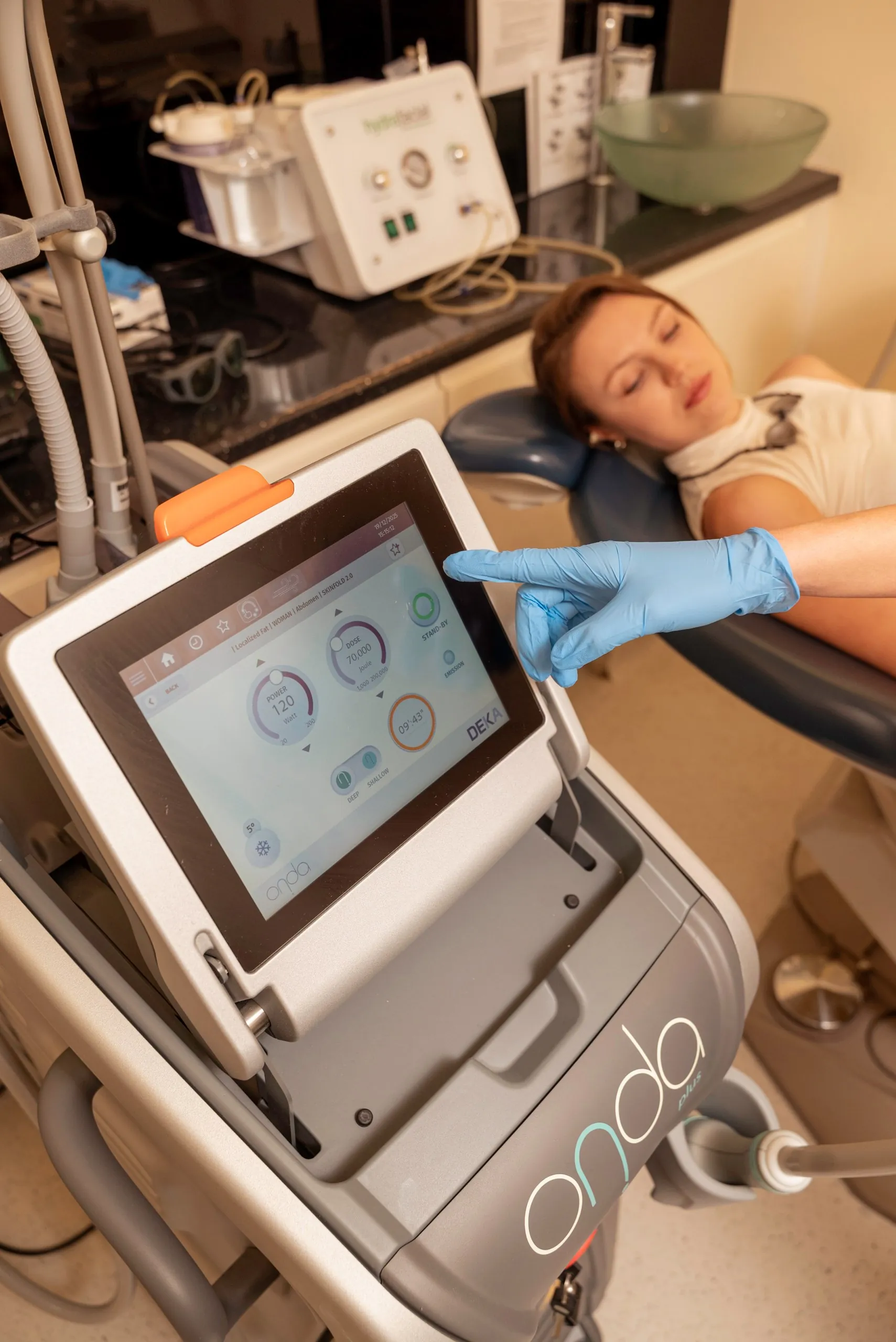 Double chin treatment in Islington, London: therapist setting up the Onda machine beside a reclining patient