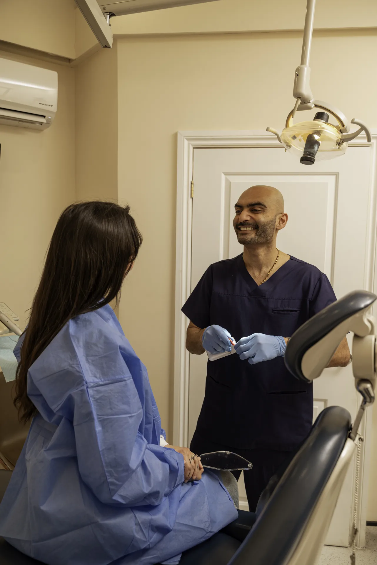 Plinest in Islington, London: dentist talking with a patient in a treatment gown in the surgery