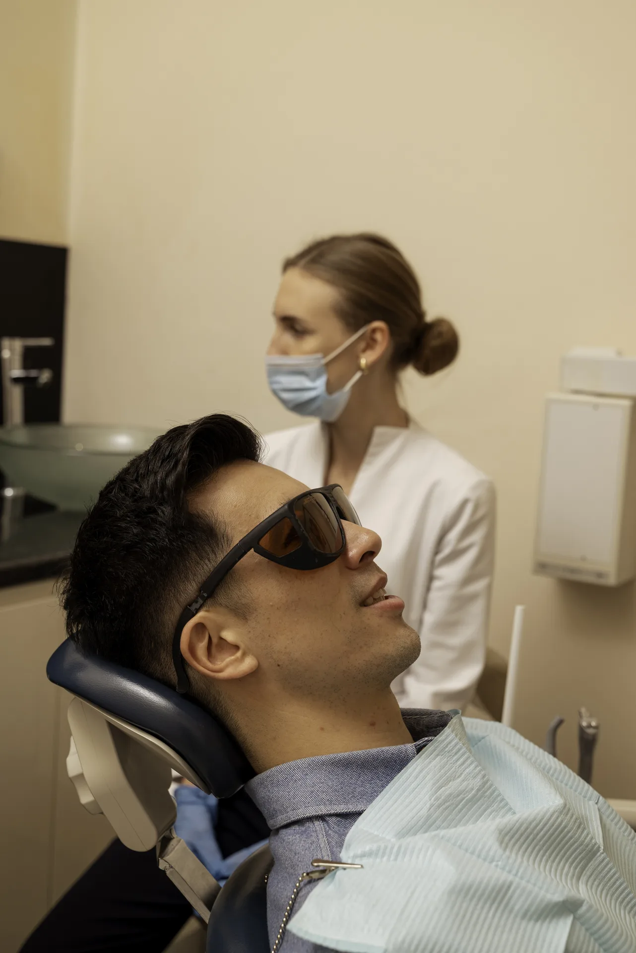 Biological dentistry in Islington: patient in protective glasses reclining in the dental chair with a nurse beside him
