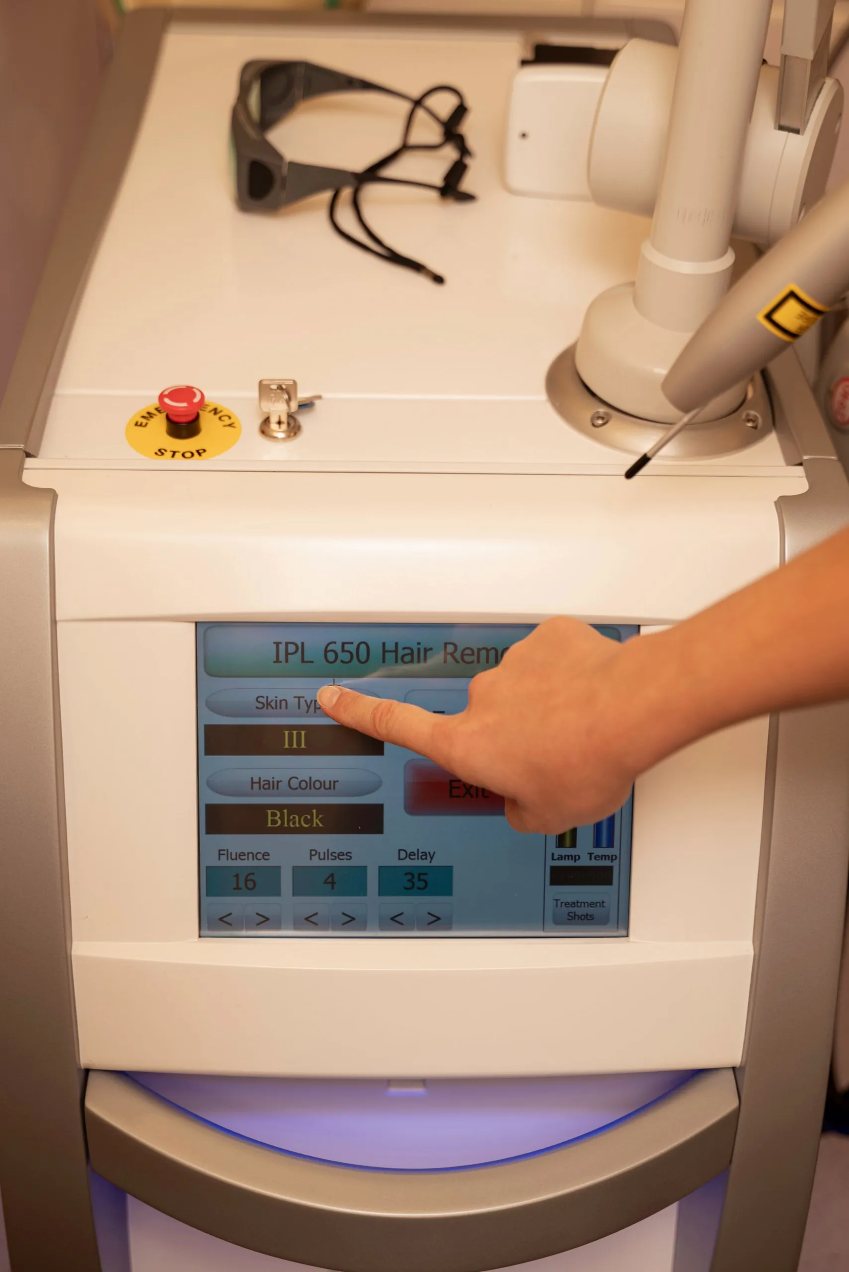 Clinician adjusting settings on the touchscreen of a laser machine — coloured tattoo removal