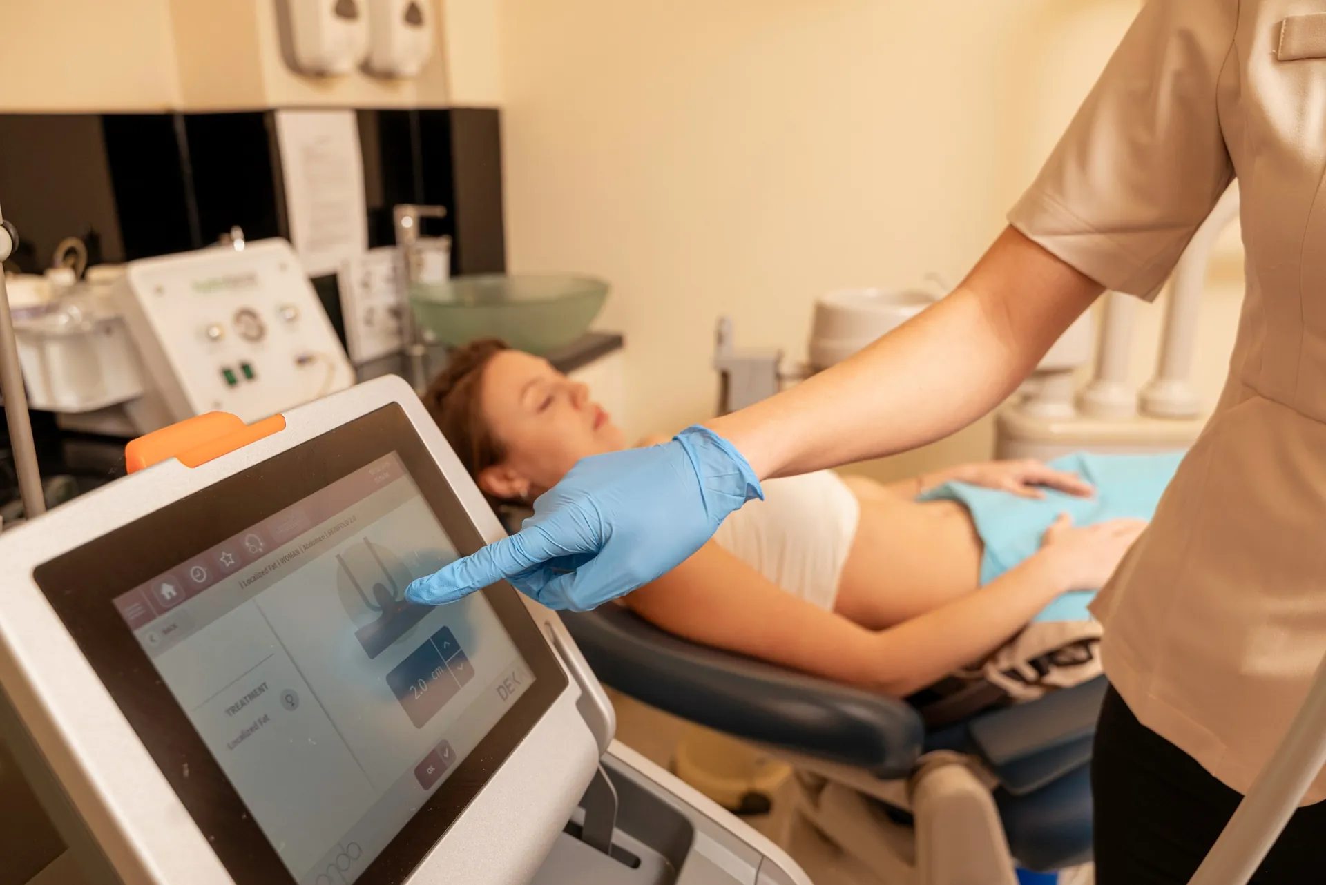 Therapist setting up an Onda body treatment on a reclining patient's abdomen