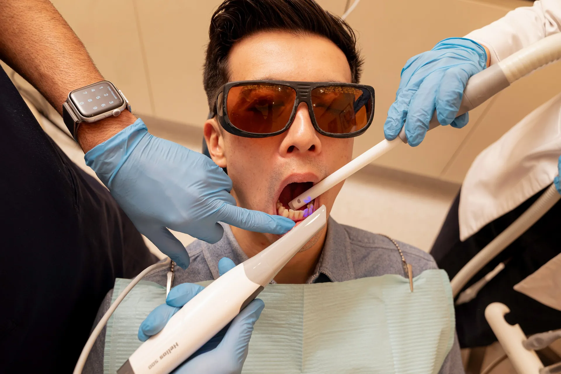 Patient in protective glasses having a curing light used on his teeth