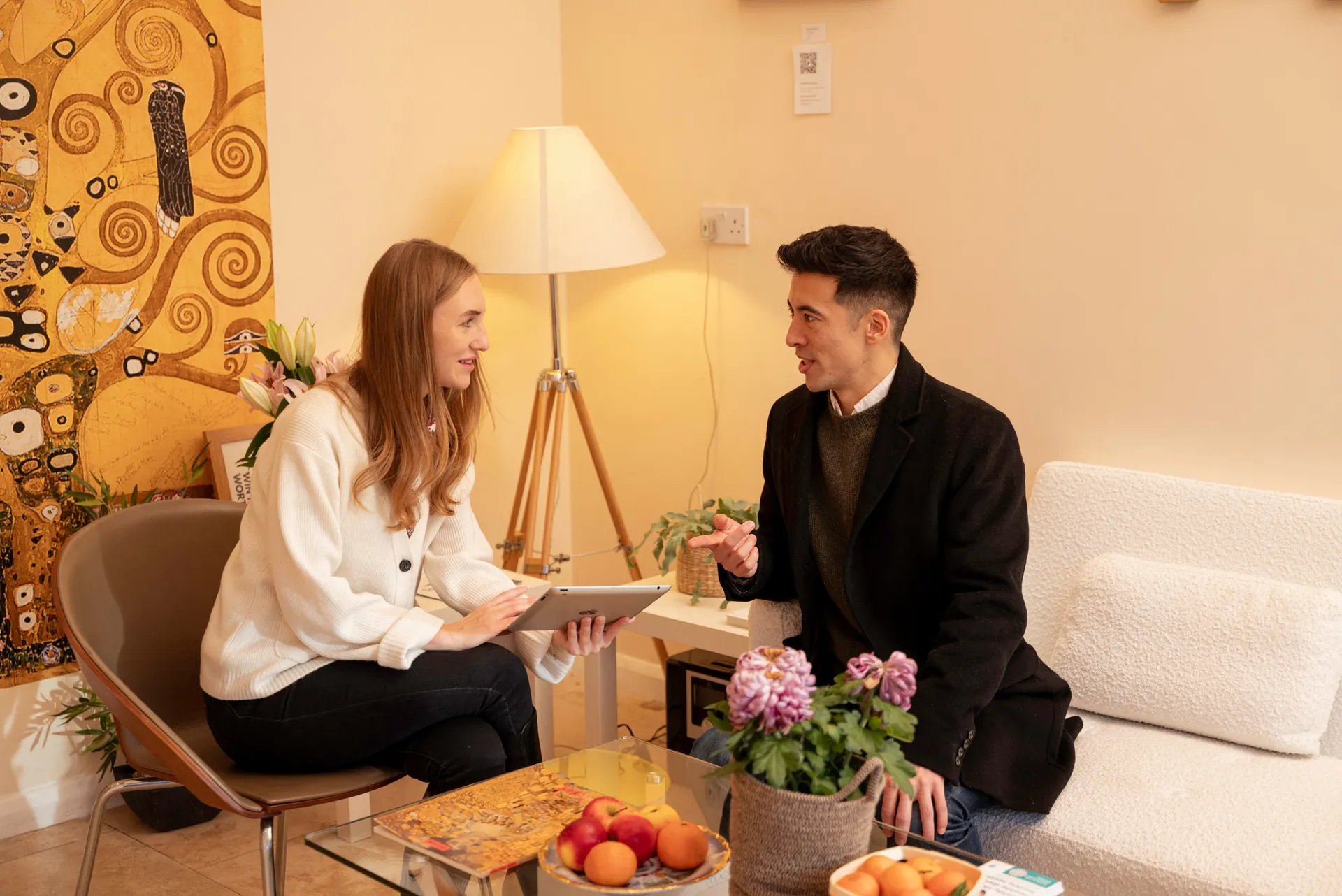 Practitioner and client in consultation over a tablet in the clinic lounge