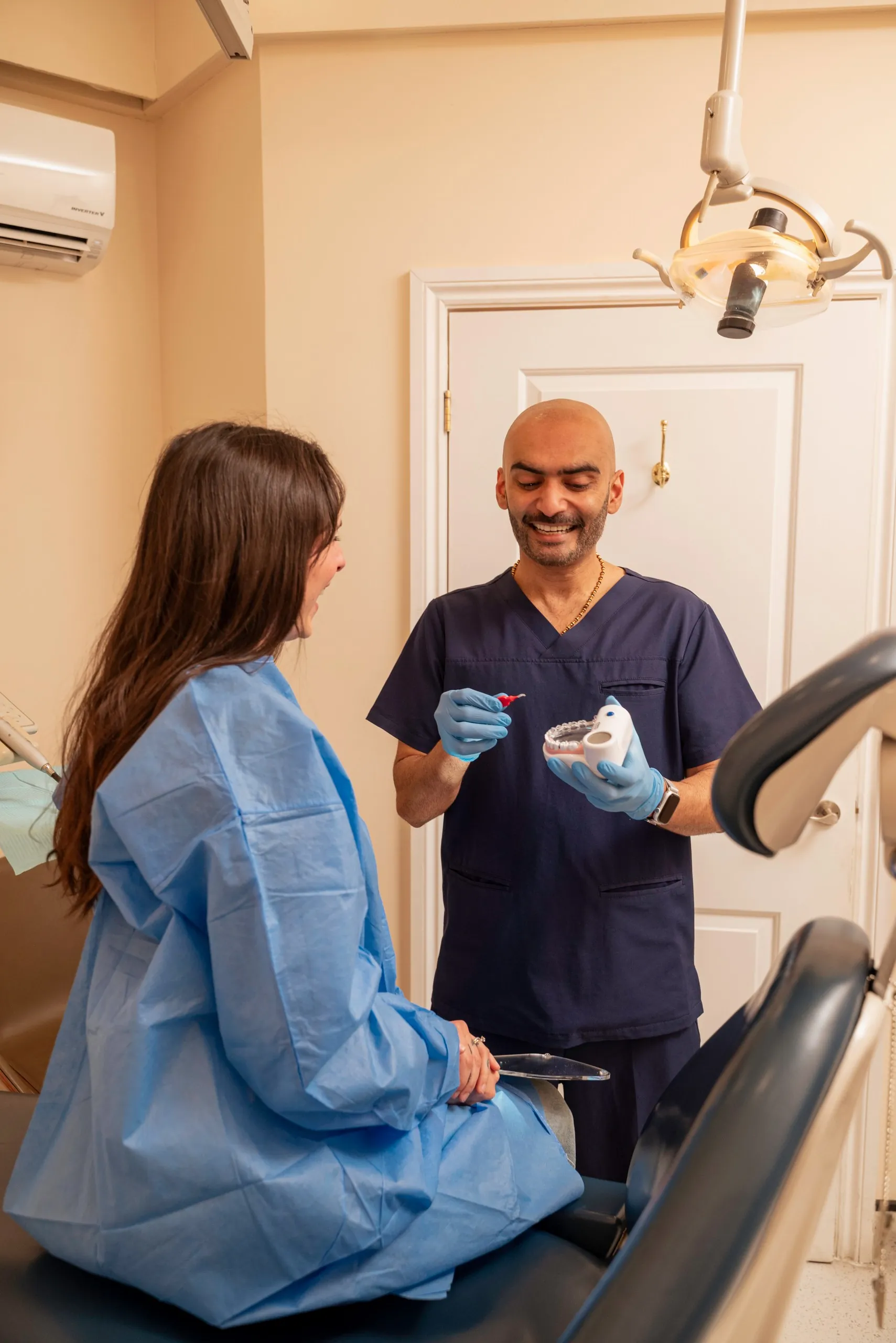 Dentist talking with a patient in a treatment gown in the surgery