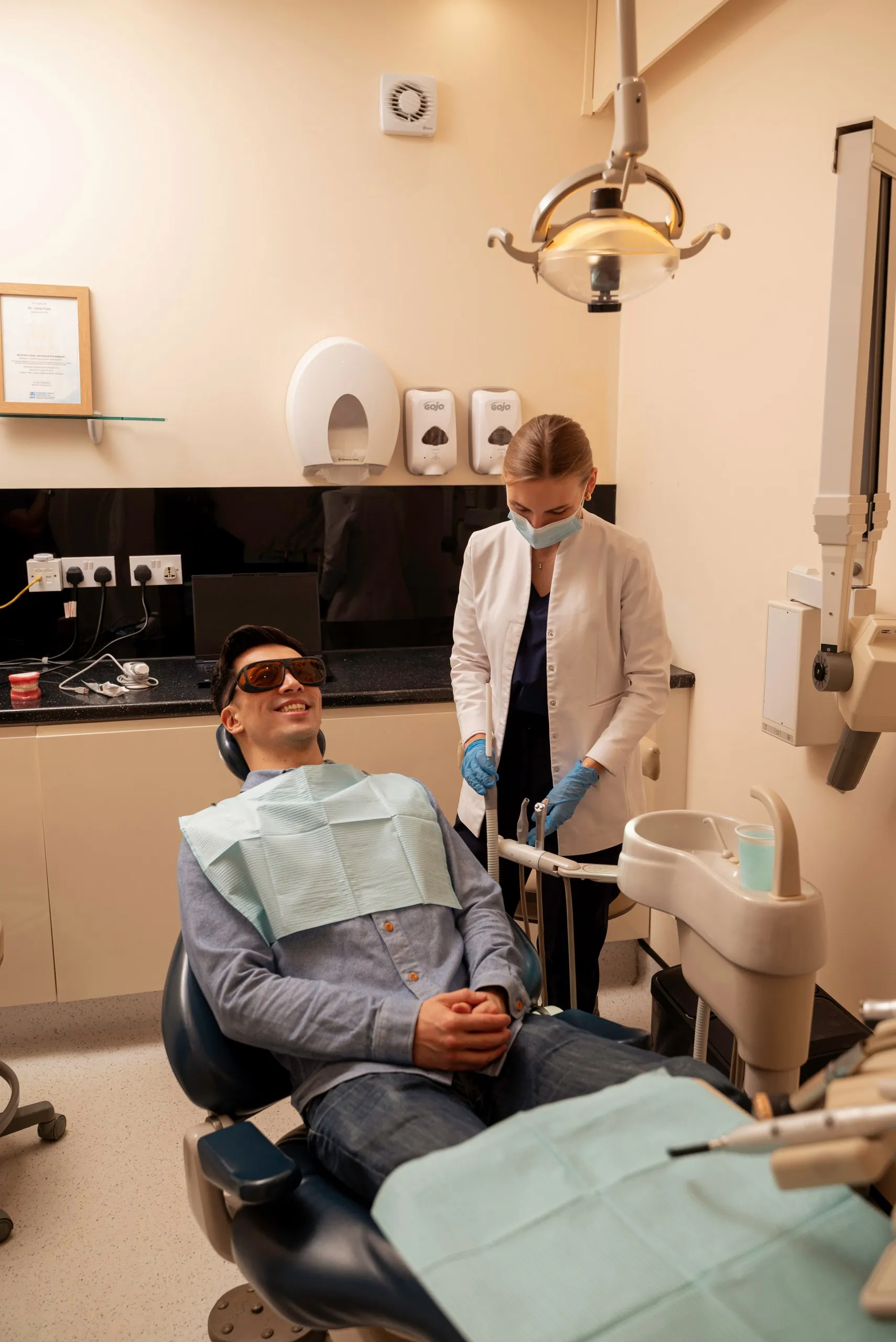 Composite bonding: patient in protective glasses in the dental chair with a nurse beside him