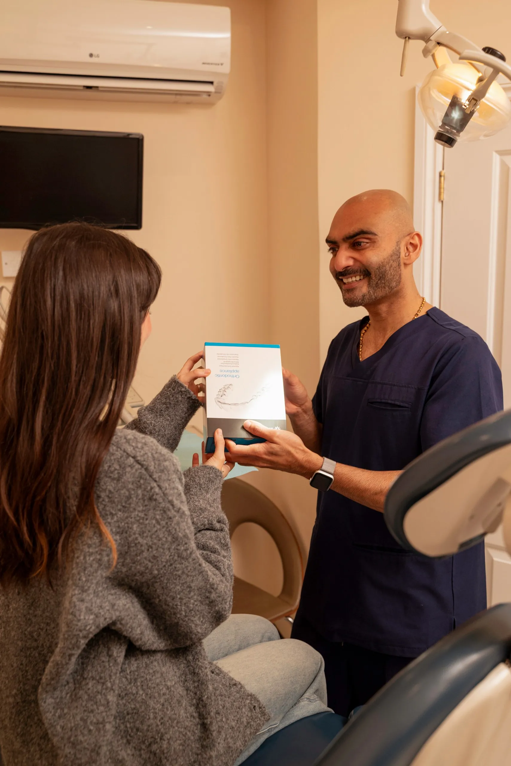 Dentist handing a patient her aligner box in the surgery